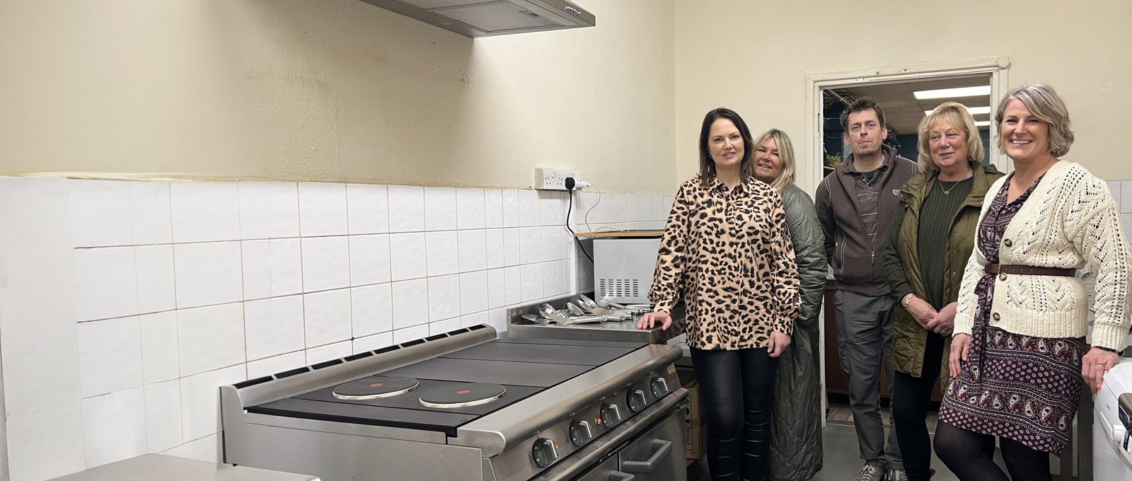Photo of a group of people from Futures and the charity Salcare in the kitchen at Salcare alongside the newly installed cooker