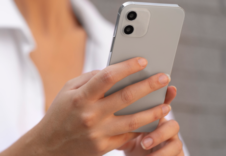Close up photo of a woman wearing a white blouse holding a smartphone.
