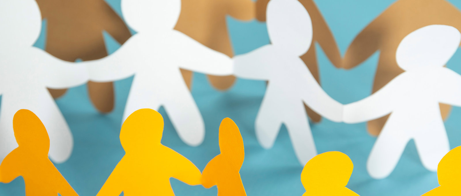 Simple white and yellow paperchain cut-outs of people holding hands arranged in alternating rows of yellow and white
