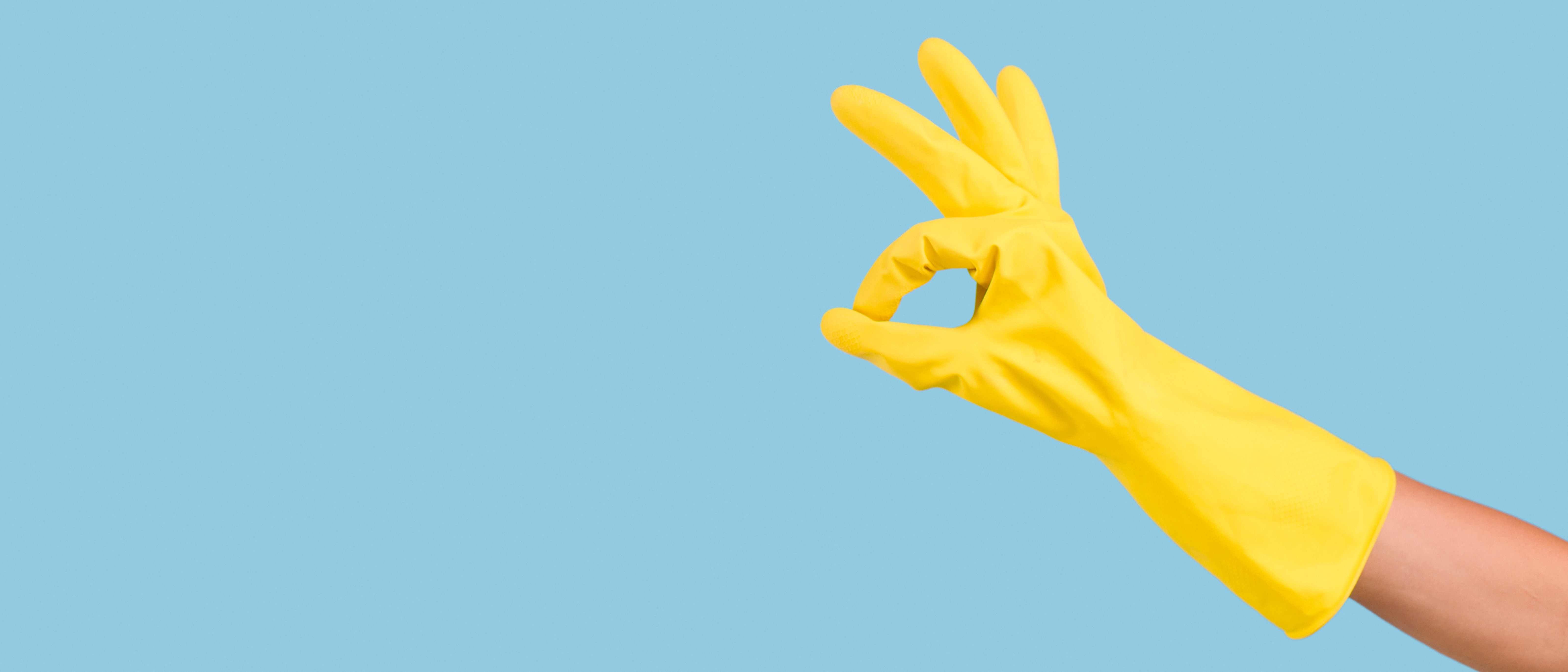 Hand wearing a yellow rubber glove showing the okay gesture