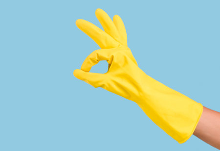 Hand wearing a yellow rubber glove showing the okay gesture
