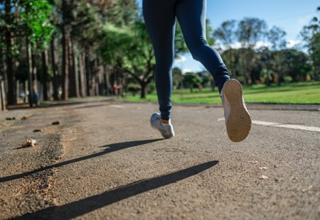 Close up photo of a woman's lower legs and feet taken as she jogs along a pathway in a park