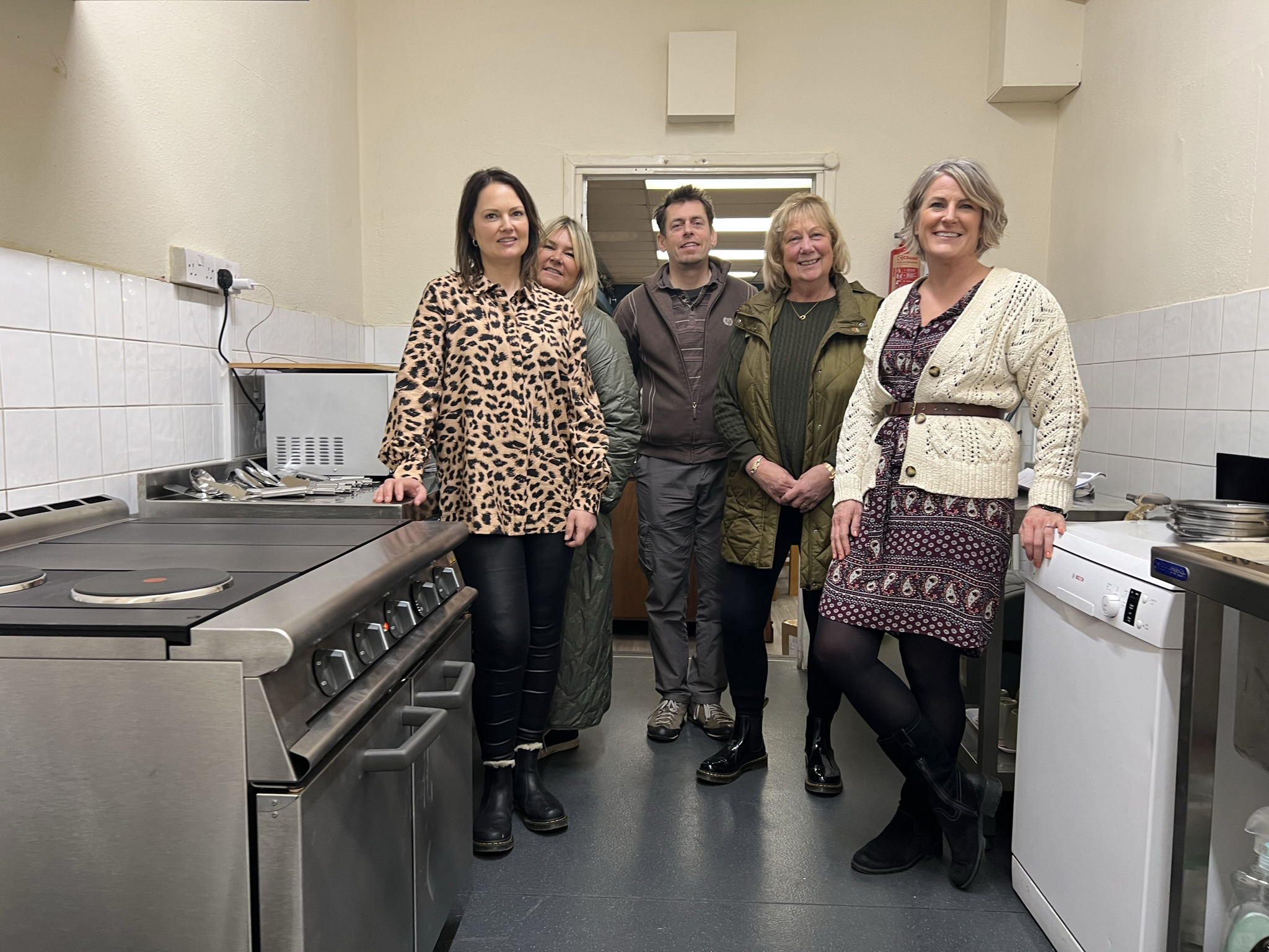 Photo of a group of people from Futures and the charity Salcare in the kitchen at Salcare alongside the newly installed cooker