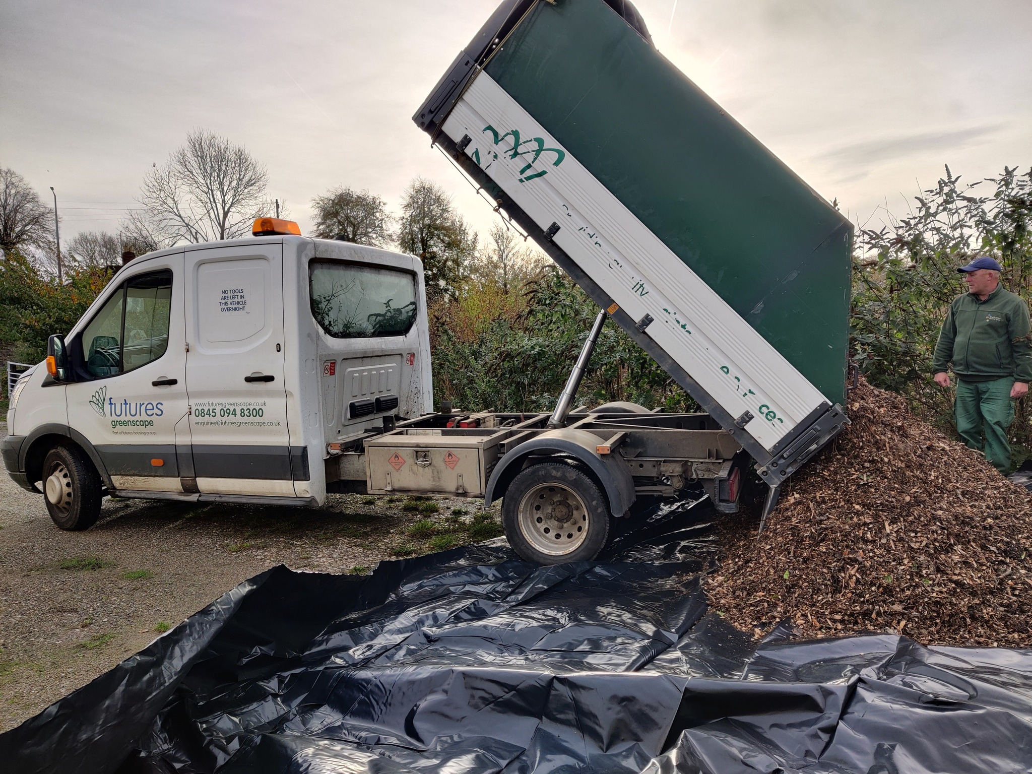 Photograph of an open back truck unloading a pile of tree bark chippings onto the ground
