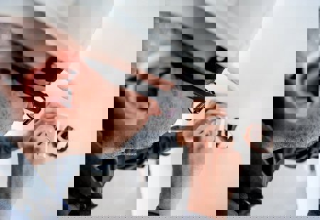 Close up photo of a man in a white hard hat installing an electrical socket in a wall